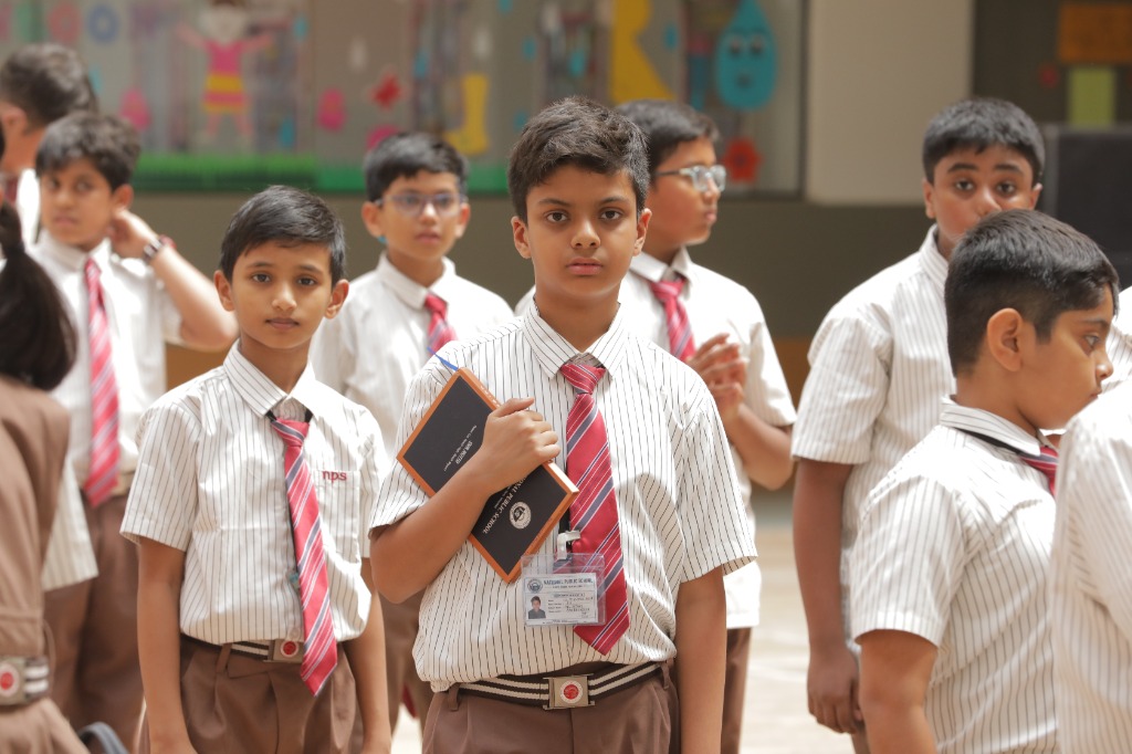 Student holding NPS handbook at National Public School Hopefarm
